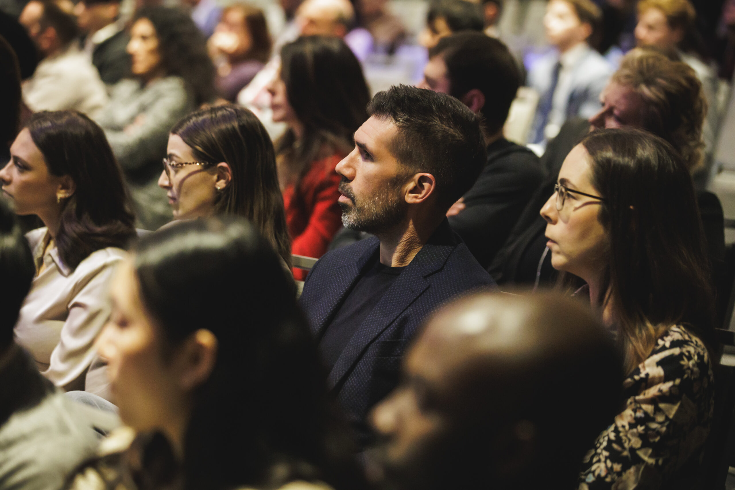 Audience eagerly awaiting the reveal of a mystery guest speaker at CRECTalk, discussing insights on real estate.